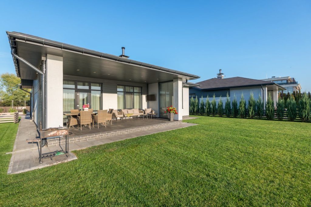 A modern house with a wide patio and neatly landscaped backyard, ideal for real estate and architecture themes.